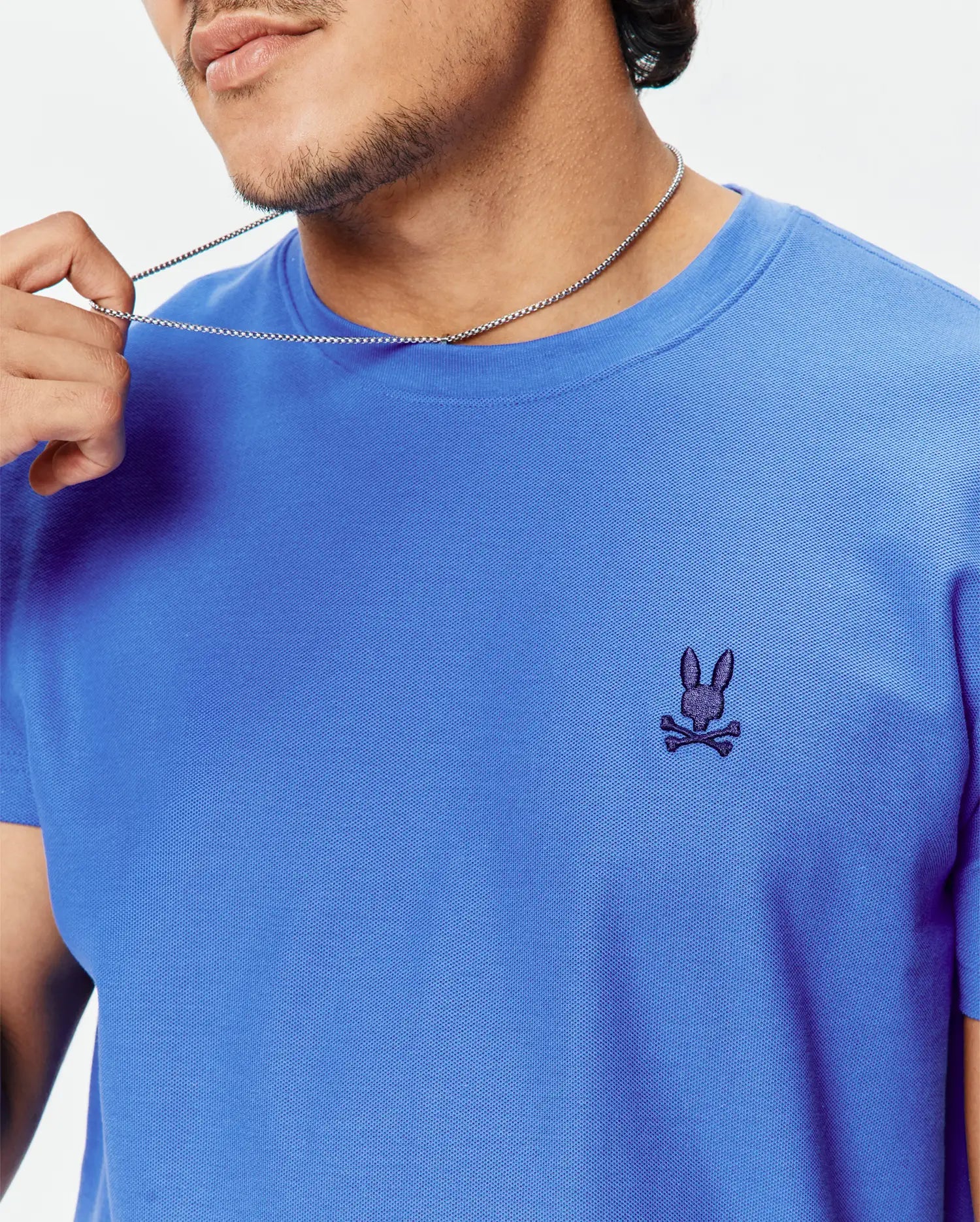 Mens Taylor Pique Tee, vibrant blue classic fit with a visible pique texture, featuring a small dark indigo embroidered Psycho Bunny skull logo on the left chest.