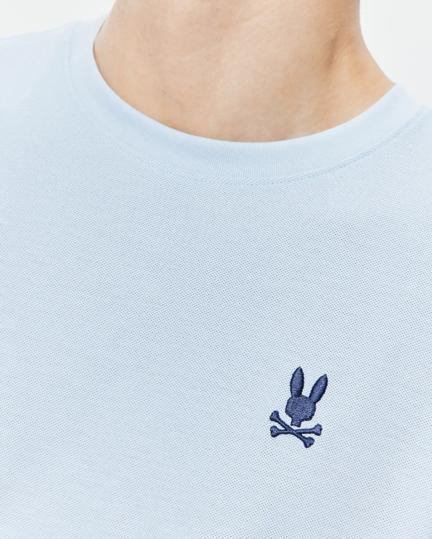 Light blue Mens Taylor Pique Tee, a classic fit shirt in textured pique fabric, featuring a small, embroidered dark blue Psycho Bunny skull logo on the left chest.