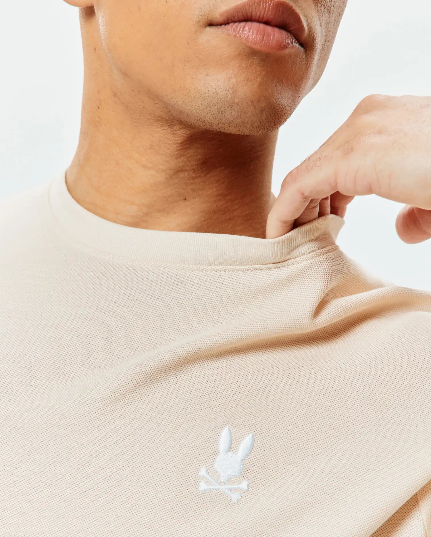 Mens Taylor Pique Tee in cream, featuring a classic fit and pique texture, with a small white embroidered Psycho Bunny skull logo on the left chest.