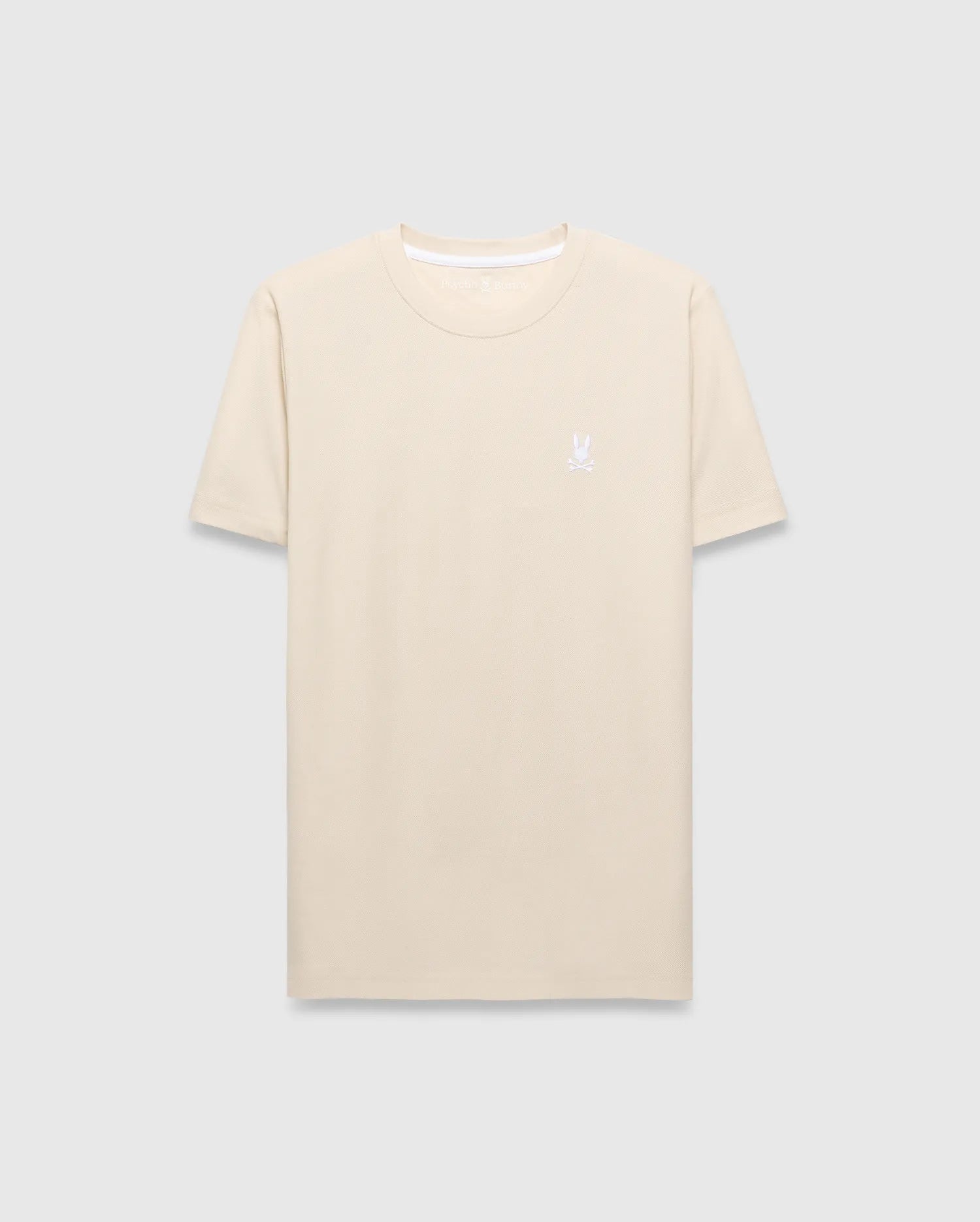 Mens Taylor Pique Tee in cream, featuring a classic fit and subtle pique texture. A small, white embroidered Psycho Bunny skull logo adorns the left chest.