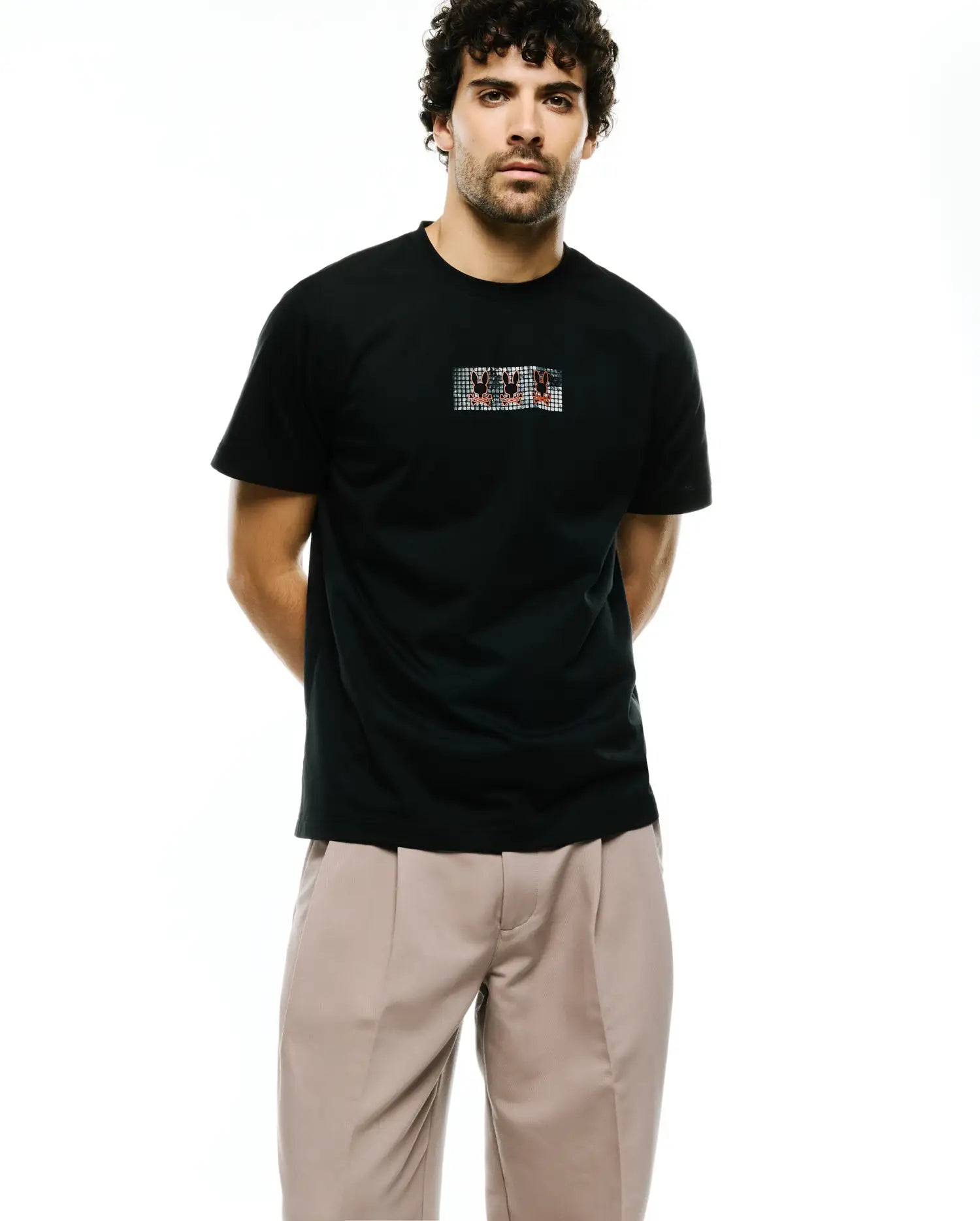 Men's Alfie Back Graphic Tee, a classic fit black jersey t-shirt featuring a small central chest graphic of multiple red and white Psycho Bunny skull logos in a grey grid pattern. (2)