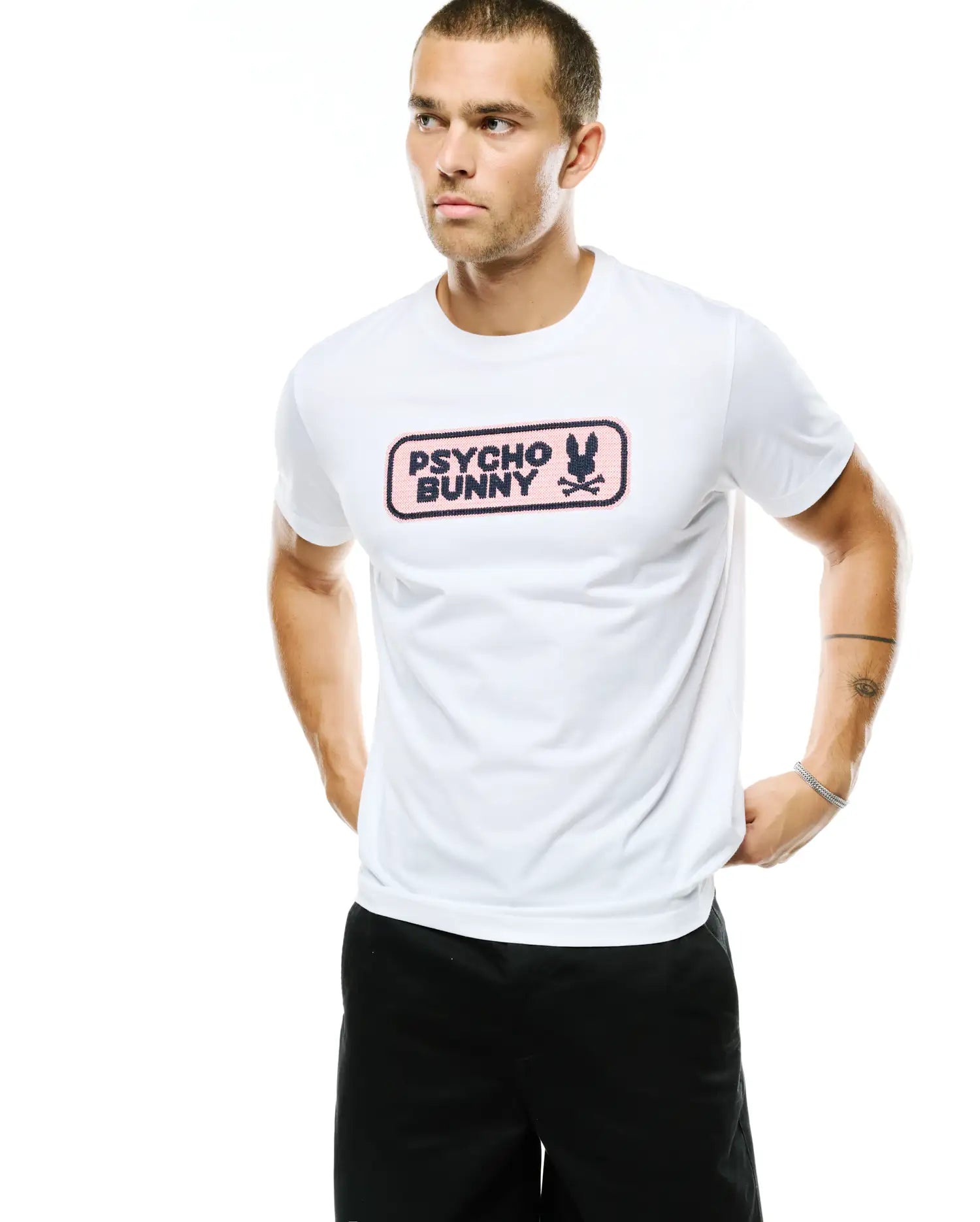 Men's Samson Wordmark Graphic Tee, a classic fit white jersey t-shirt with a prominent chest graphic featuring a pink rectangular background, dark blue Psycho Bunny wordmark, and bunny skull logo. (4)