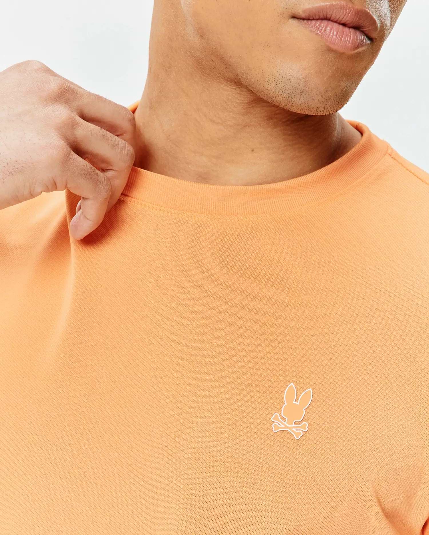 Mens Dash Bunny Sport Tee in peach orange pique knit, featuring a small white embroidered Psycho Bunny skull logo on the left chest for a classic fit.