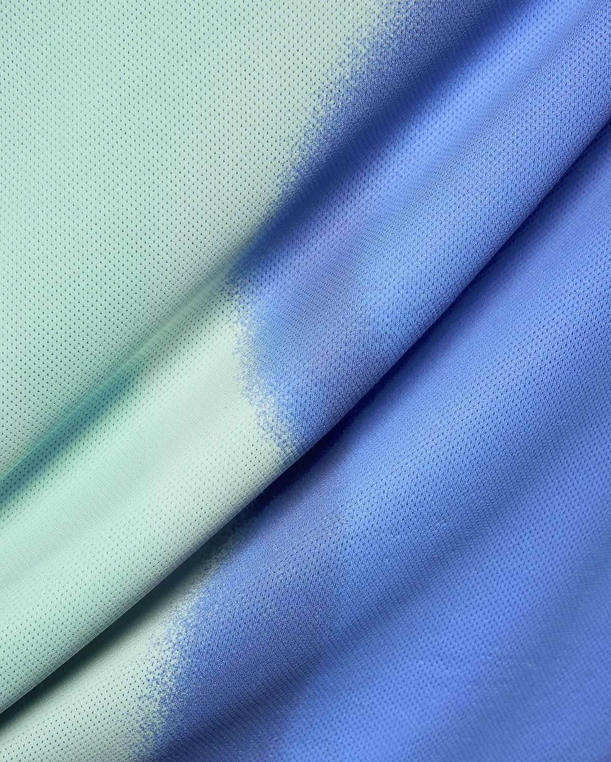 Mens Blaze Sport Tee in a perforated mesh fabric, featuring a vibrant gradient from aqua green to royal blue and purple, with a unique spray-dye effect. (6)