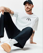 White Mens Stevie Relaxed Fit Tee in smooth jersey, featuring a black arched PSYCHO BUNNY text and iconic bunny skull logo centered on the chest.