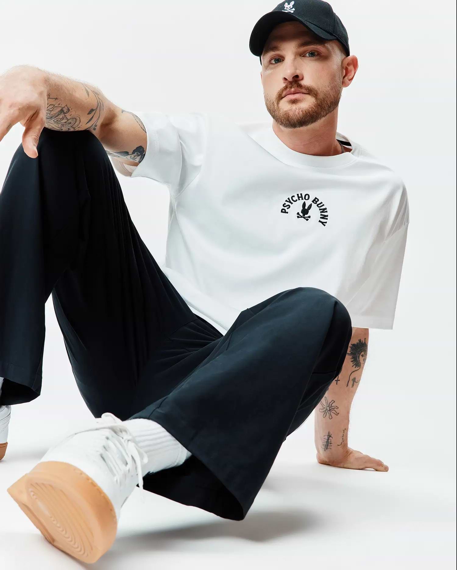 White Mens Stevie Relaxed Fit Tee in smooth jersey, featuring a black arched PSYCHO BUNNY text and iconic bunny skull logo centered on the chest.