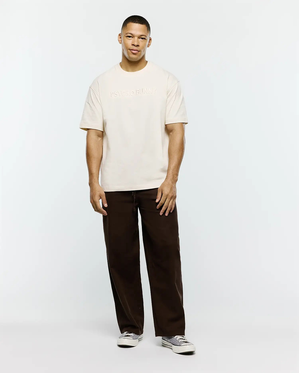 Mens Windcrest Relaxed Fit Tee in cream, crafted from soft jersey, featuring a prominent, tone-on-tone embossed PSYCHO BUNNY text logo centered on the chest. (4)