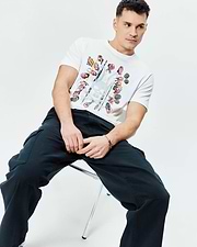Mens Race Bunny Graphic Tee: White classic fit jersey t-shirt with a large central graphic print featuring colorful race cars, drivers, and a distressed Psycho Bunny skull logo.