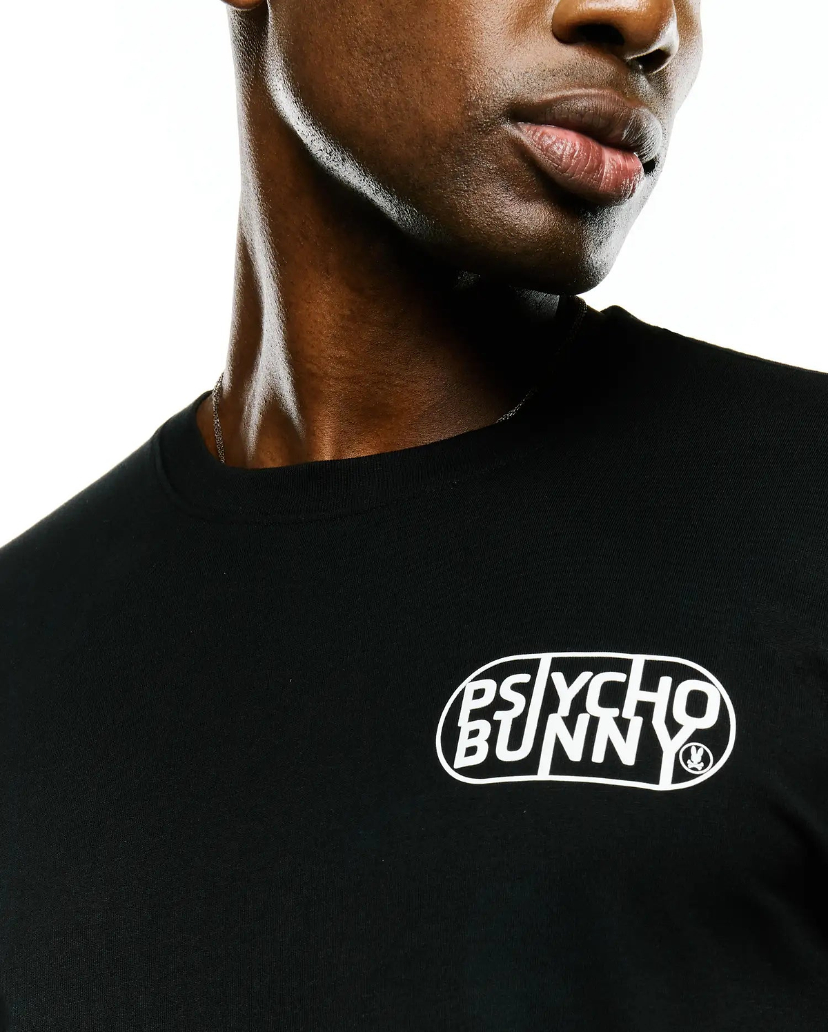 Mens Dariel Long Sleeve Back Graphic Tee in black jersey knit, featuring a white oval graphic print with stylized Psycho Bunny text and a small bunny skull logo on the front chest.
