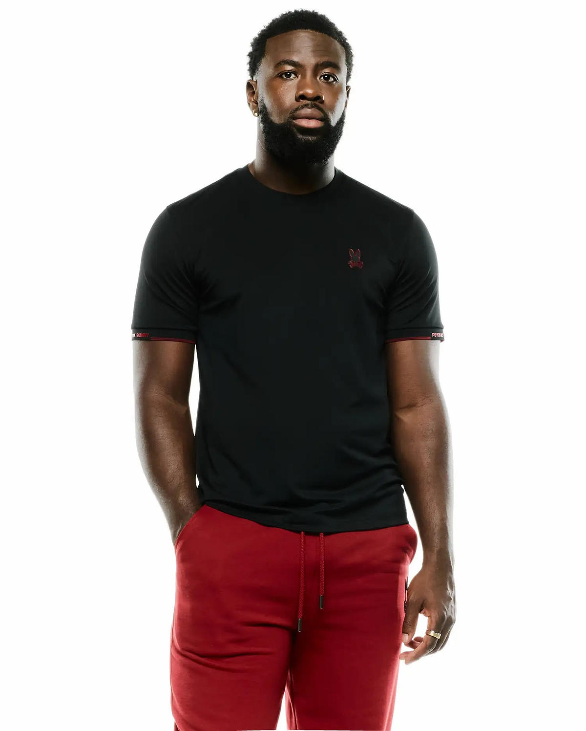 Men's Edmonds Chest Bunny Sport Tee, a black slim-fit jersey tee with a small red embroidered Psycho Bunny skull logo on the left chest, red contrast stitching, and white Psycho Bunny text on the left sleeve cuff. (1)