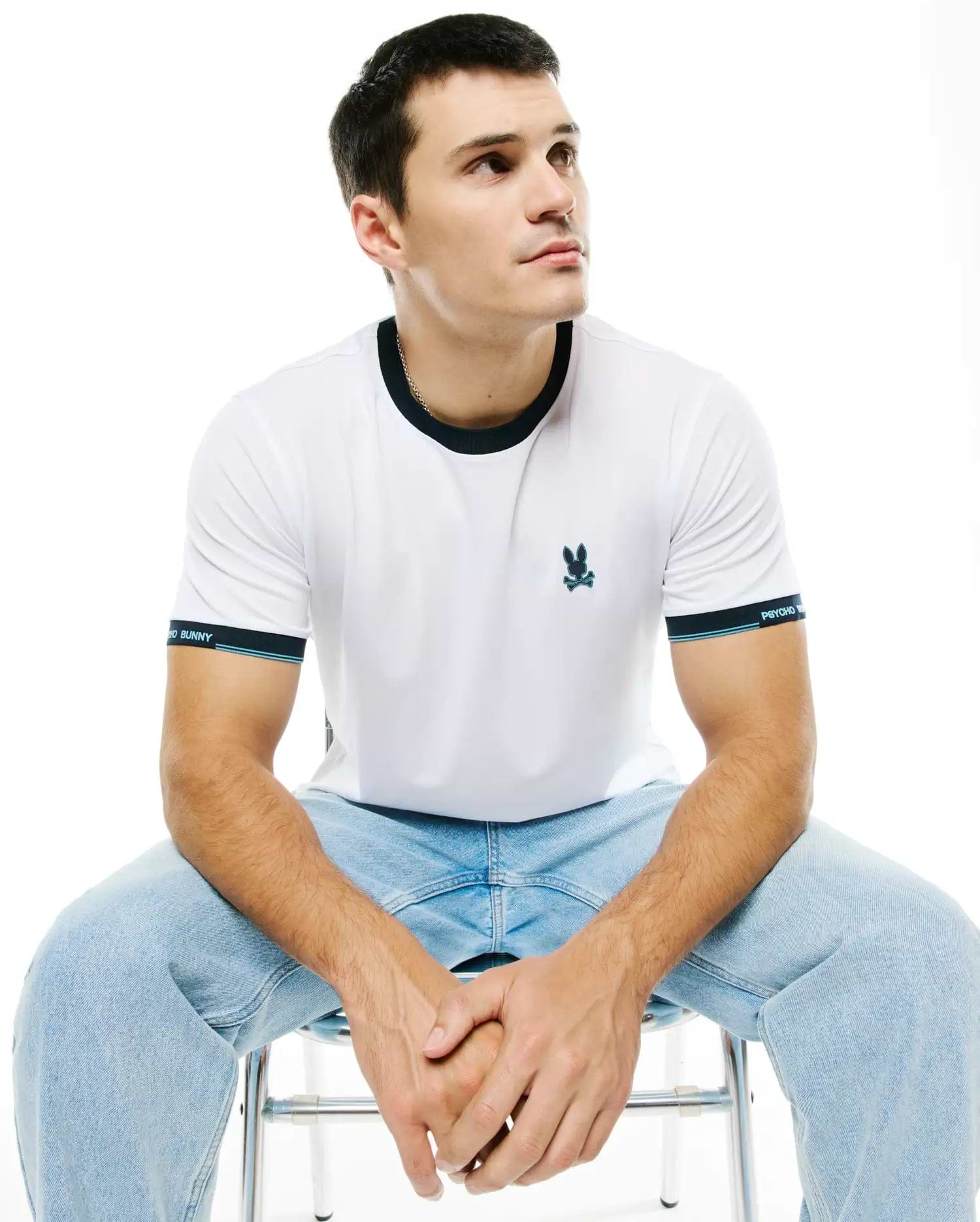 Men's Edmonds Chest Bunny Sport Tee: White jersey t-shirt with a dark blue ringer collar, banded sleeves featuring light blue stripes and Psycho Bunny text, and an embroidered teal bunny skull logo on the chest. (1)