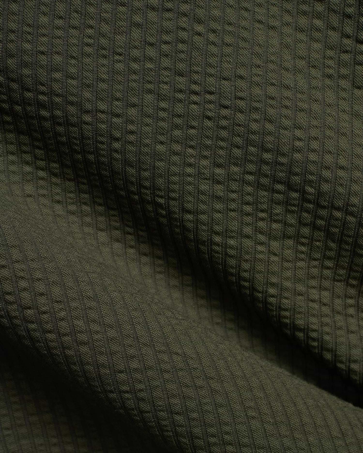 Mens Arlen Relaxed Seersucker Tee in deep olive green, showcasing its distinctive vertical puckered seersucker knit texture with subtle shadows.