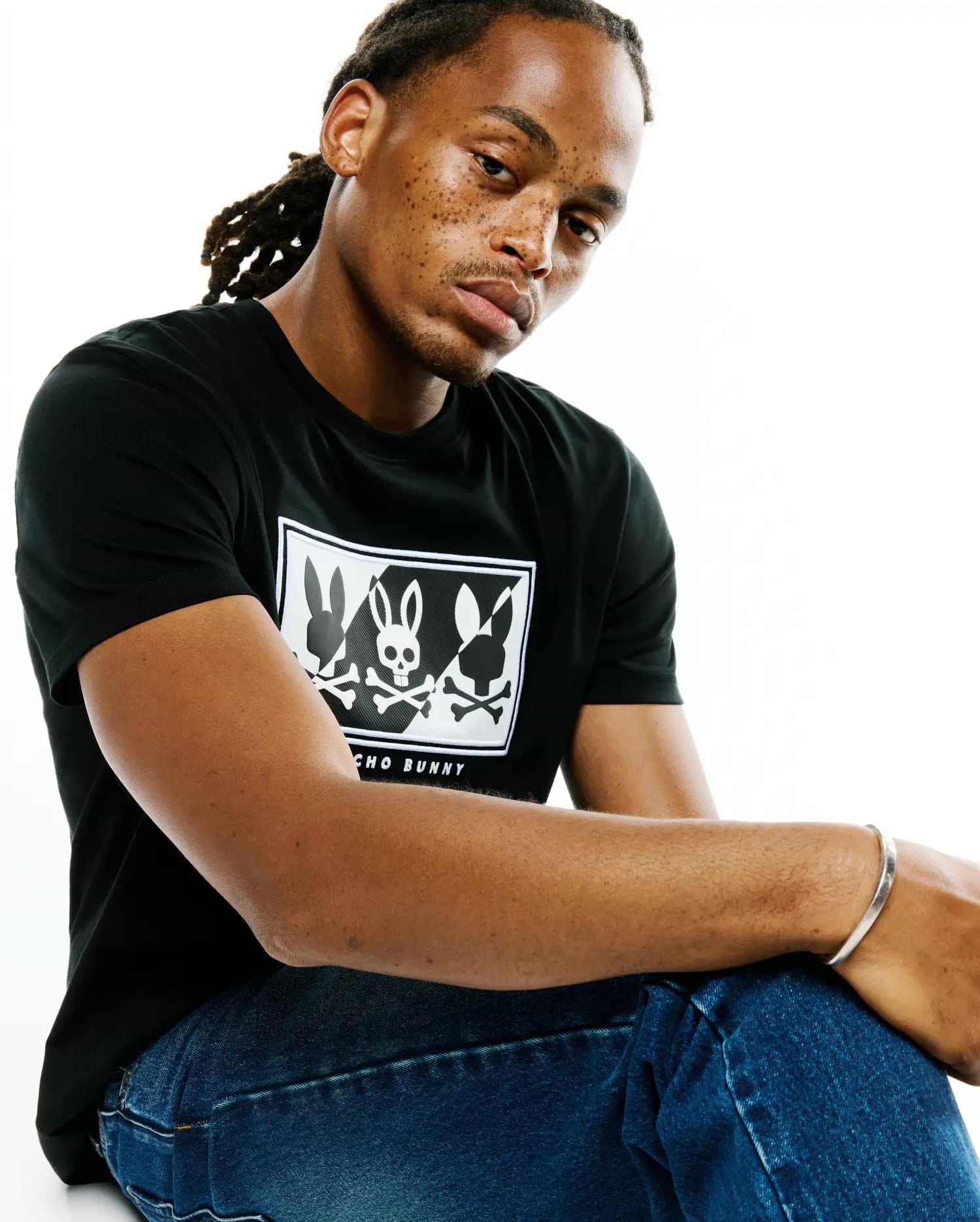 Mens Desmond Graphic Tee, black classic fit jersey t-shirt with a large white chest graphic featuring three bunny silhouettes, the central one a skull, with Psycho Bunny text below.