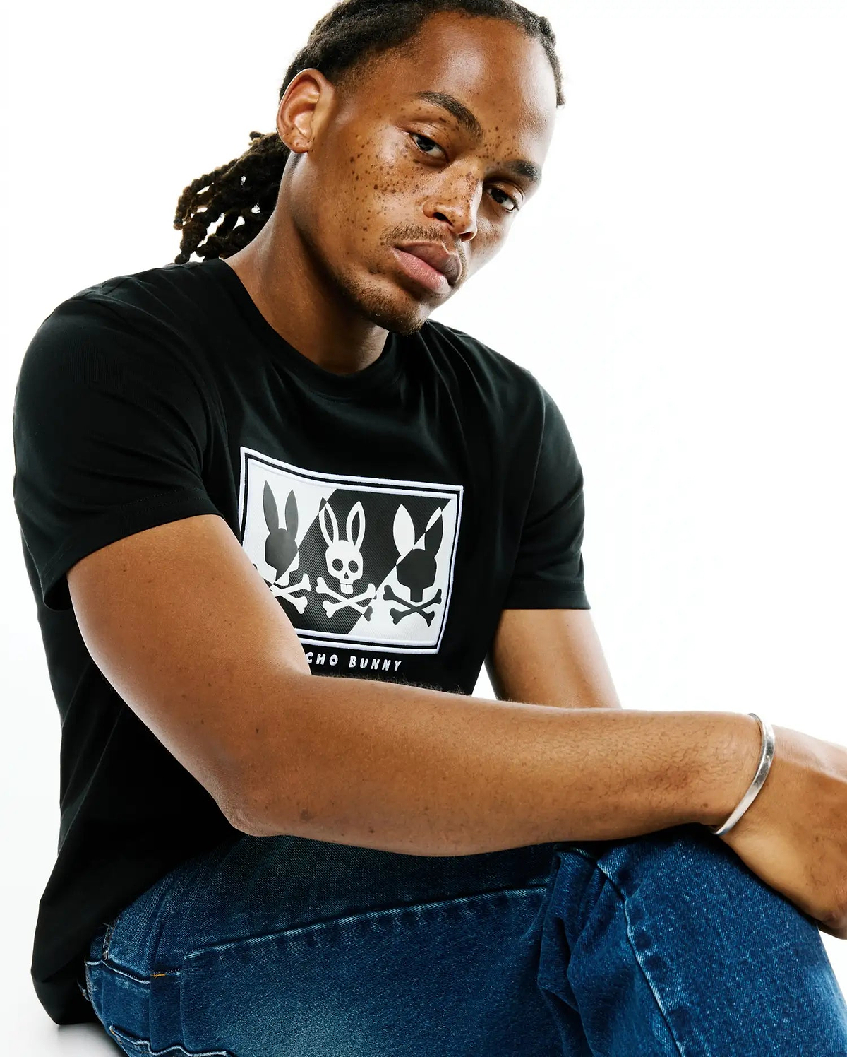 Mens Desmond Graphic Tee, black classic fit jersey t-shirt with a large white chest graphic featuring three bunny silhouettes, the central one a skull, with Psycho Bunny text below.