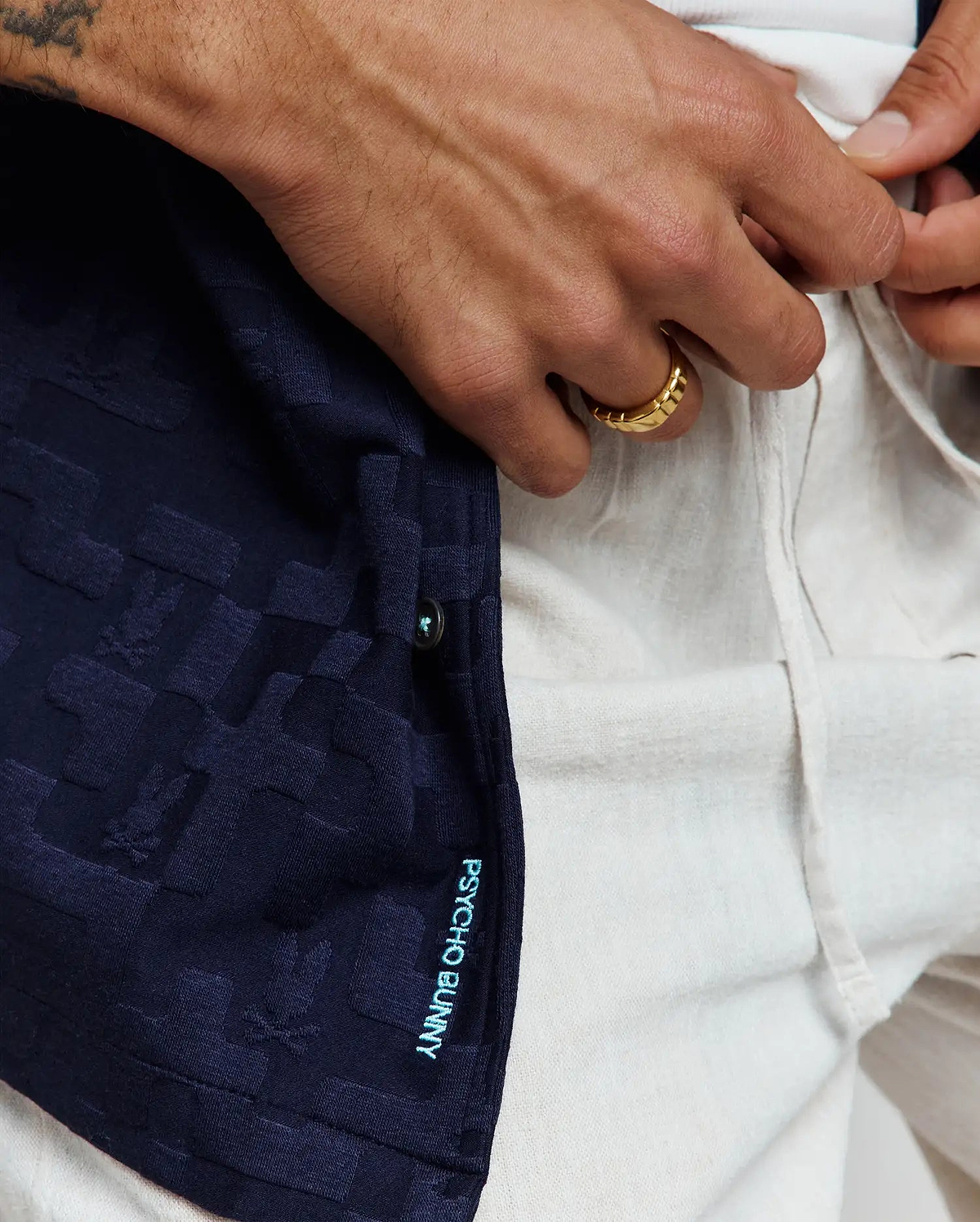Mens Josh Jacquard Shirt in navy, featuring an all-over subtle bunny skull jacquard pattern, with vertical aqua Psycho Bunny text on the placket and a light blue button detail.