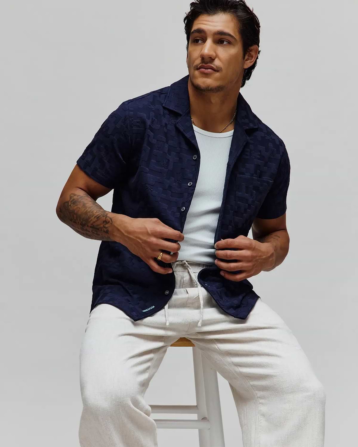 Navy blue Mens Josh Jacquard Shirt featuring a subtle tonal geometric pattern, relaxed fit, short sleeves, camp collar, and a small light blue Psycho Bunny logo on the bottom hem.
