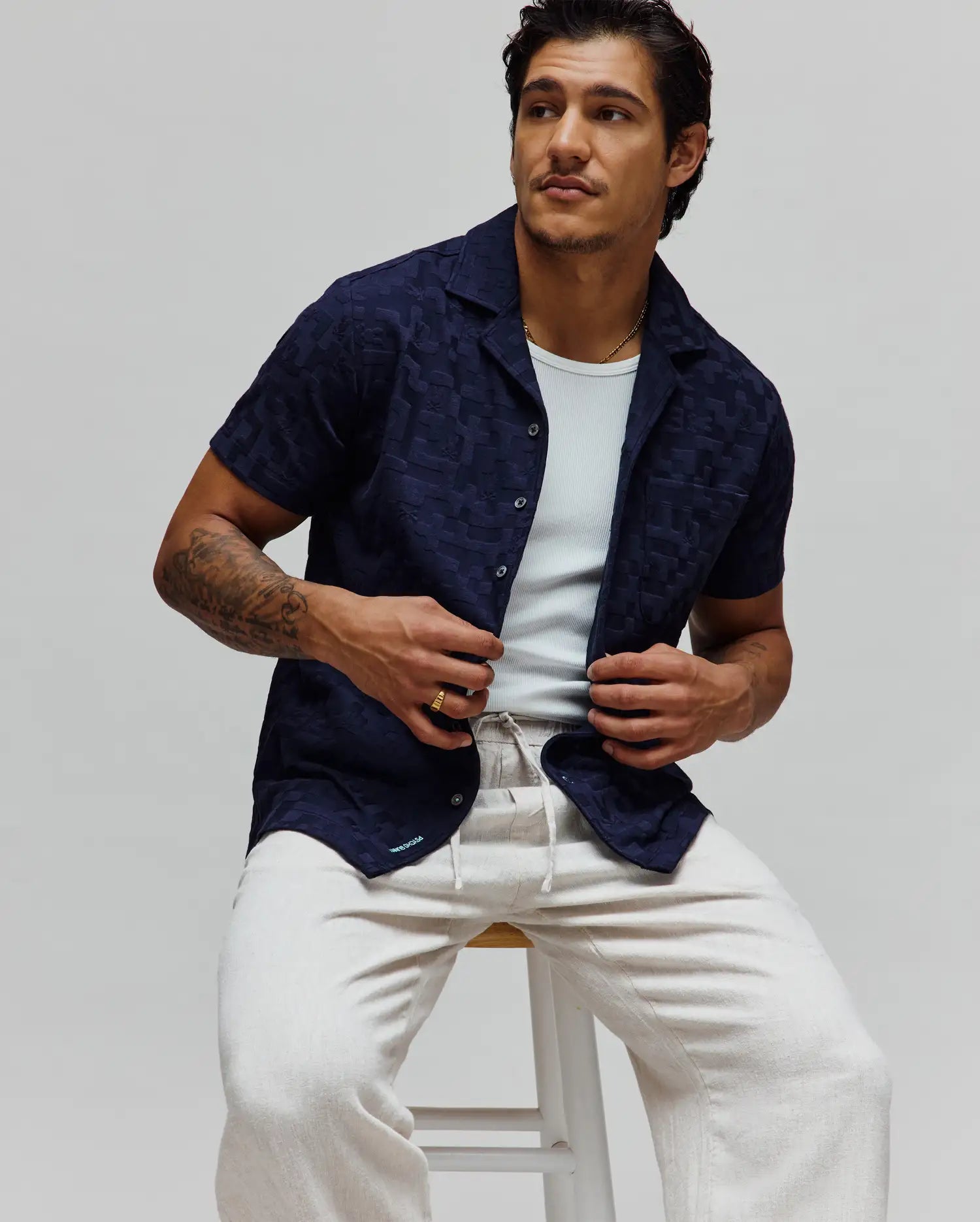 Navy blue Mens Josh Jacquard Shirt featuring a subtle tonal geometric pattern, relaxed fit, short sleeves, camp collar, and a small light blue Psycho Bunny logo on the bottom hem.