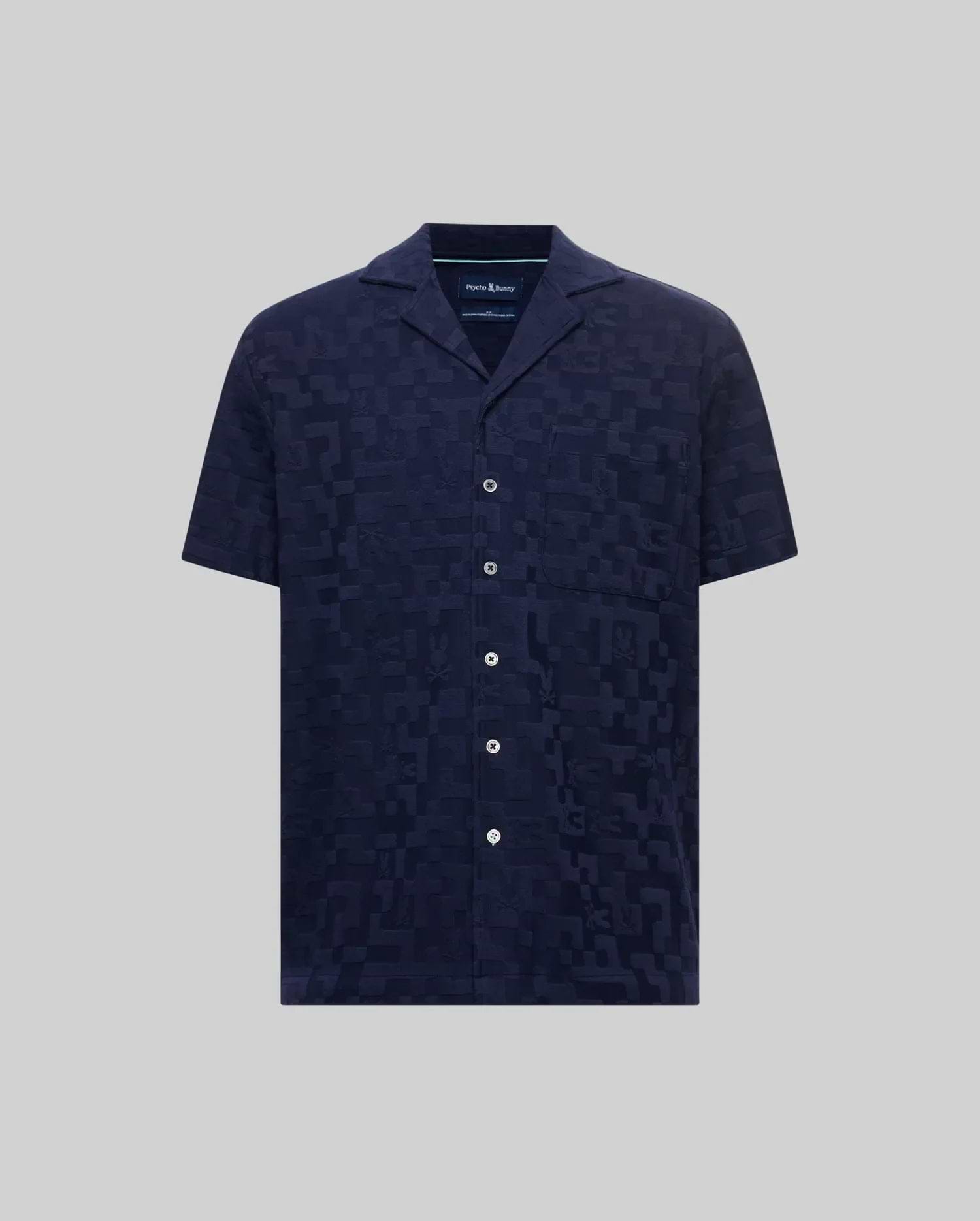 Mens Josh Jacquard Shirt, a navy blue short-sleeve camp collar shirt with a subtle all-over jacquard pattern featuring the Psycho Bunny skull logo and geometric shapes, classic fit, white buttons.