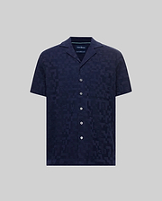 Mens Josh Jacquard Shirt, a navy blue short-sleeve camp collar shirt with a subtle all-over jacquard pattern featuring the Psycho Bunny skull logo and geometric shapes, classic fit, white buttons.