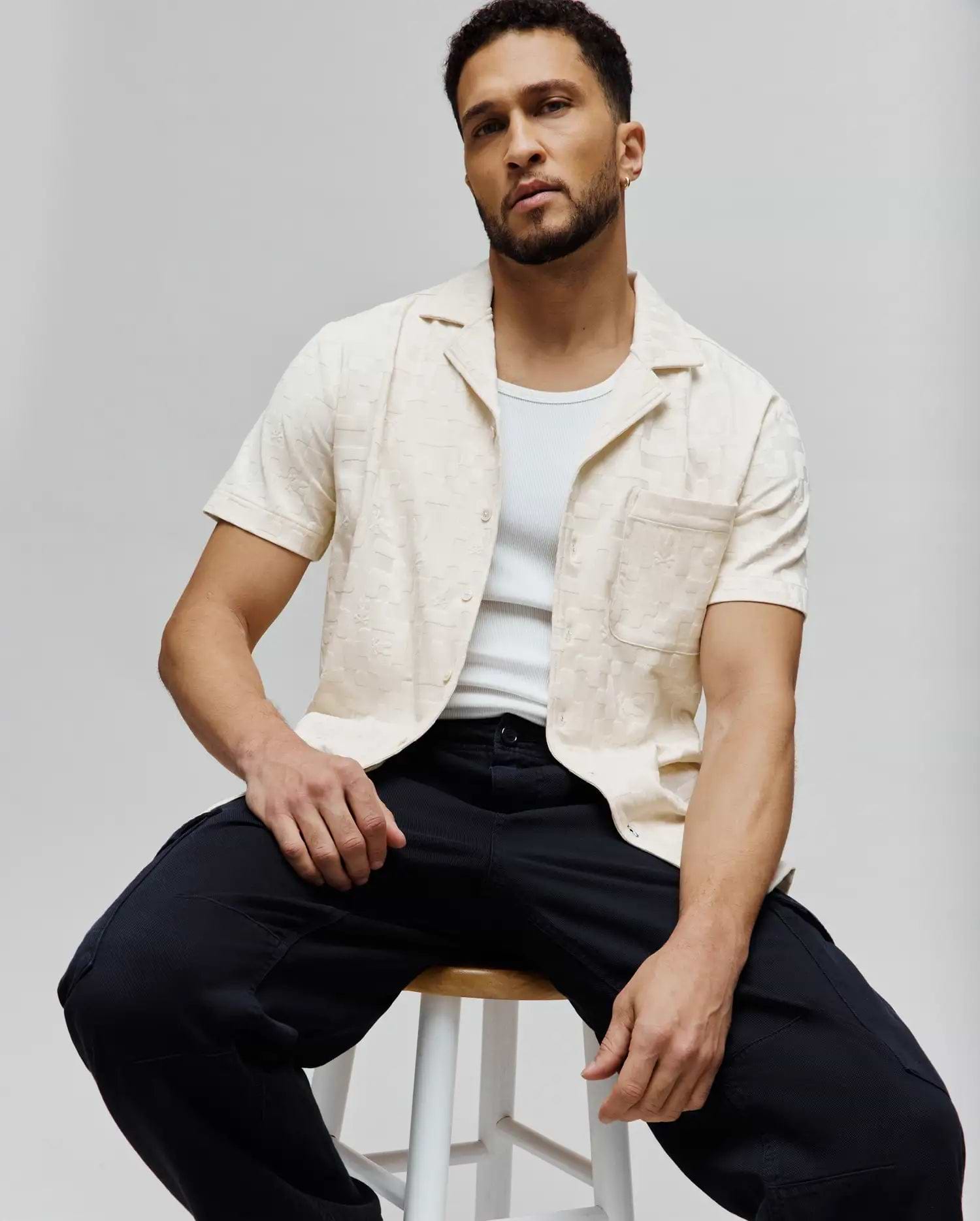 Mens Josh Jacquard Shirt, a relaxed fit cream short-sleeve button-up with a subtle all-over Psycho Bunny skull jacquard pattern, camp collar, and left chest pocket.