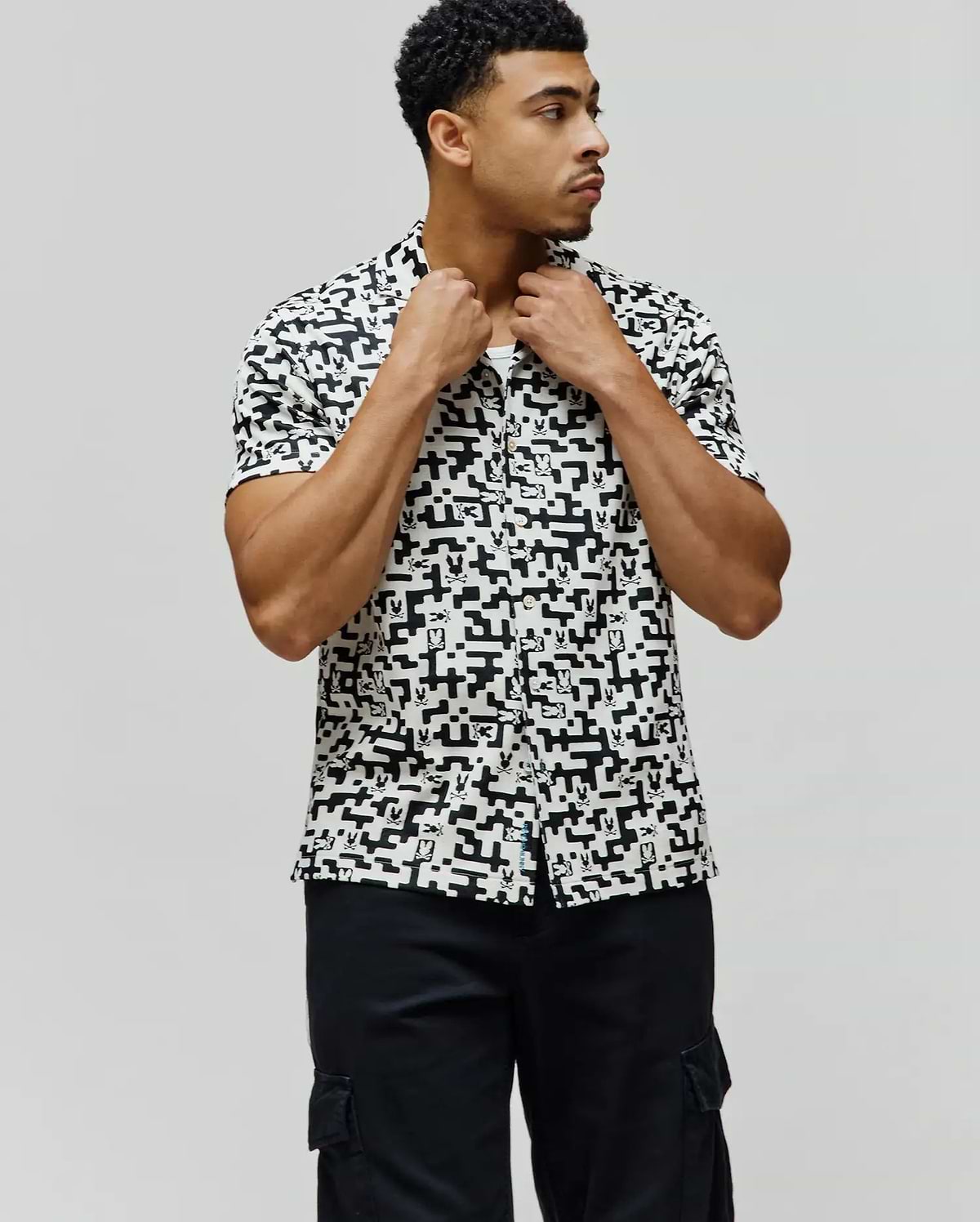 Mens Josh Jacquard Shirt, a classic fit short-sleeve button-up, in white with an all-over black geometric pixelated pattern subtly incorporating the iconic Psycho Bunny skull logo.