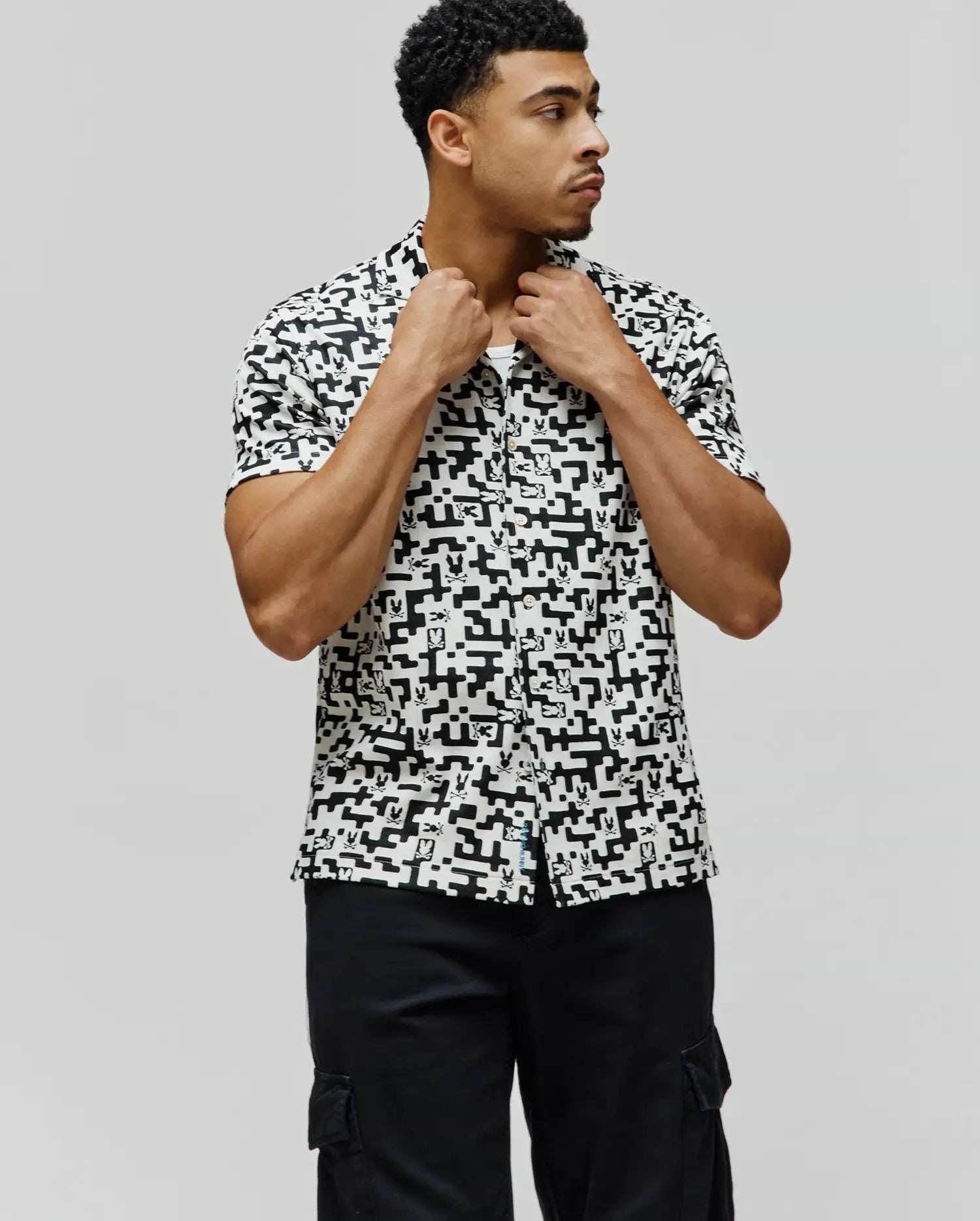 Mens Josh Jacquard Shirt, a classic fit short-sleeve button-up, in white with an all-over black geometric pixelated pattern subtly incorporating the iconic Psycho Bunny skull logo.
