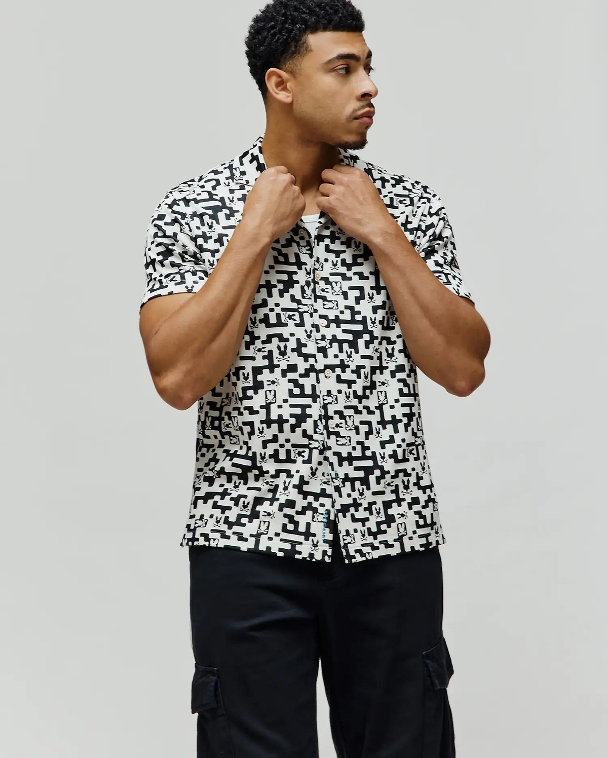Mens Josh Jacquard Shirt, a classic fit short-sleeve button-up, in white with an all-over black geometric pixelated pattern subtly incorporating the iconic Psycho Bunny skull logo.