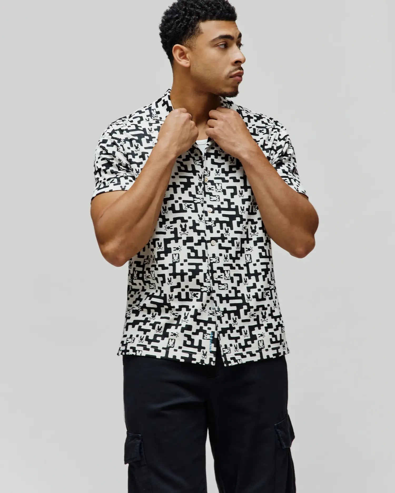Mens Josh Jacquard Shirt, a classic fit short-sleeve button-up, in white with an all-over black geometric pixelated pattern subtly incorporating the iconic Psycho Bunny skull logo.