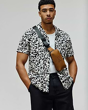 Mens Josh Jacquard Shirt, a relaxed fit white short-sleeve button-up with an all-over black geometric and small Psycho Bunny skull logo jacquard pattern.