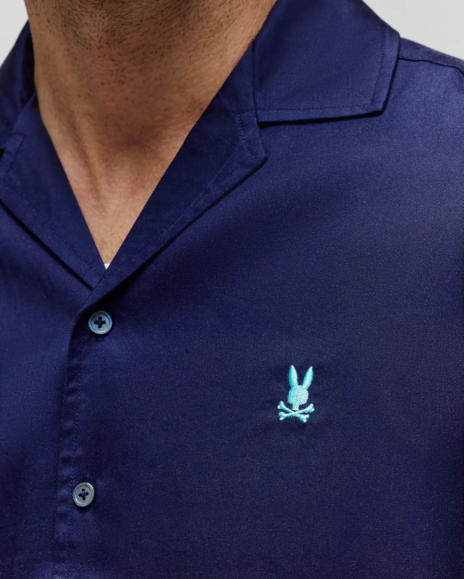 Mens Dax Tencel Shirt in navy blue, featuring a classic fit, smooth Tencel fabric, camp collar, and a small embroidered light blue Psycho Bunny skull logo on the left chest.