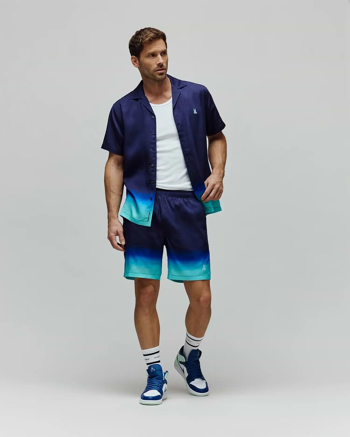 Mens Dax Tencel Shirt and matching shorts, both featuring a navy to teal ombre design, relaxed fit, smooth fabric, and small embroidered Psycho Bunny skull logos on the chest and leg.