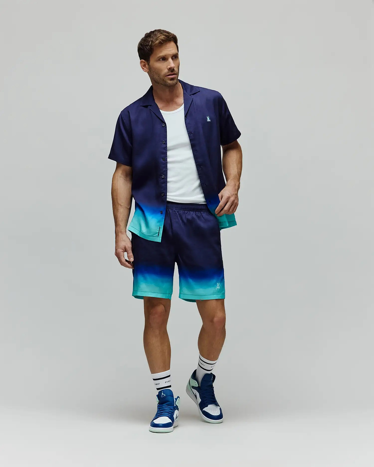 Mens Dax Tencel Shirt and matching shorts, both featuring a navy to teal ombre design, relaxed fit, smooth fabric, and small embroidered Psycho Bunny skull logos on the chest and leg.