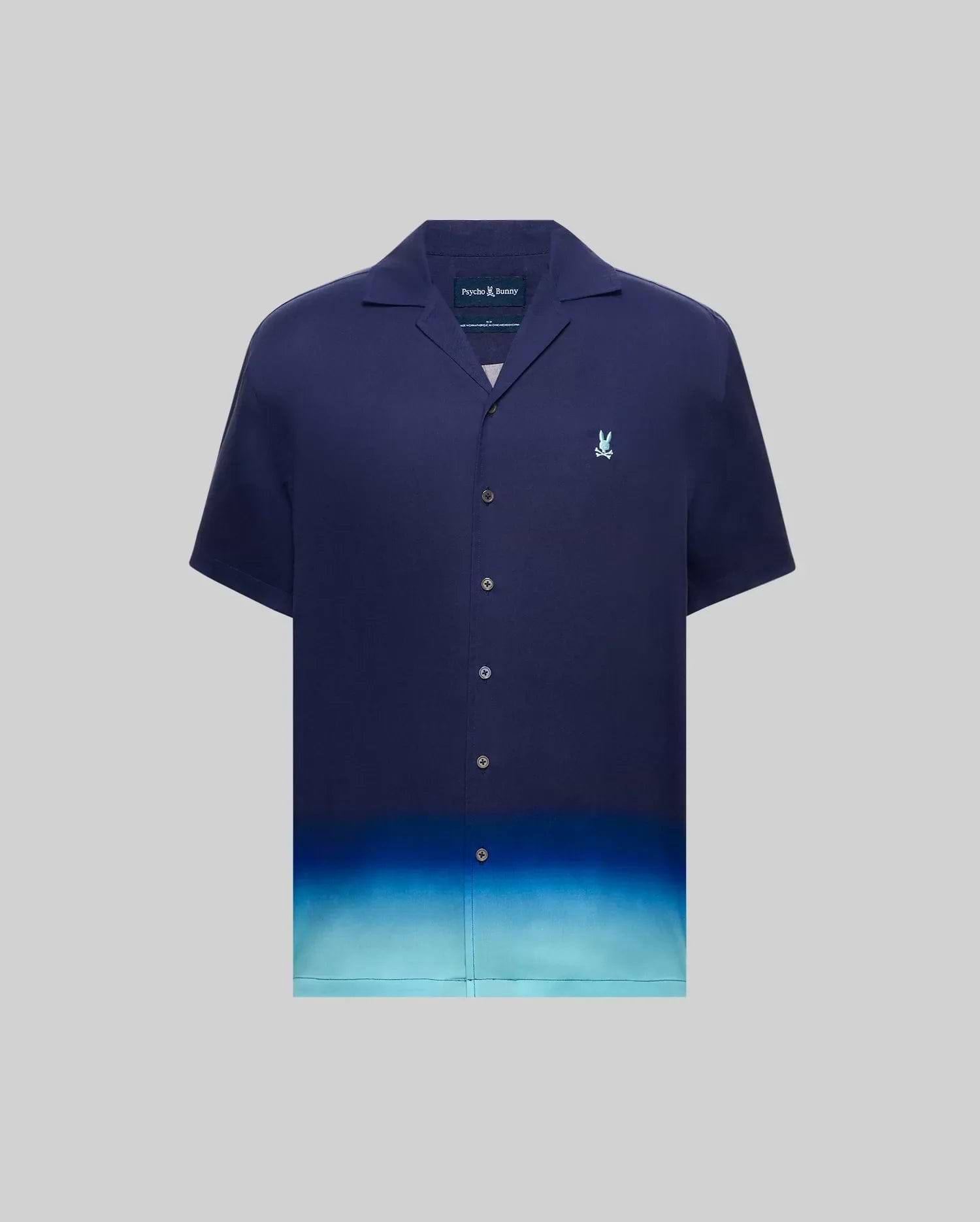 MENS DAX TENCEL SHIRT, a relaxed fit navy blue short-sleeve camp collar shirt with an ombre gradient fading to light blue at the hem and a small embroidered Psycho Bunny skull logo on the left chest.