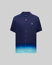 MENS DAX TENCEL SHIRT, a relaxed fit navy blue short-sleeve camp collar shirt with an ombre gradient fading to light blue at the hem and a small embroidered Psycho Bunny skull logo on the left chest.