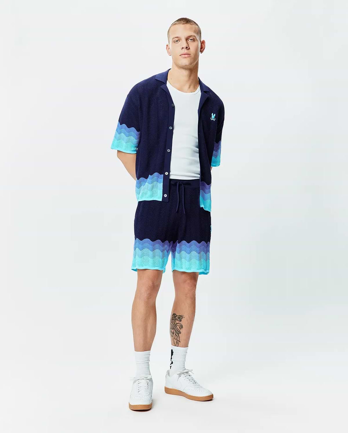 Mens Holden Oversized Knit Shirt and matching knit shorts, navy with wavy aqua and light blue gradient pattern. Oversized knit texture, small aqua embroidered Psycho Bunny skull logo on left chest.