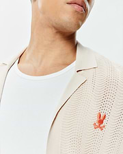 Mens Holden Relaxed Fit Knit Shirt, cream with a collared neckline and open-knit wavy texture, featuring a small embroidered orange Psycho Bunny skull logo on the left chest.