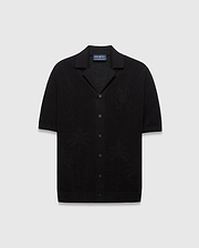Mens Brad Oversized Knit Shirt in black, featuring a textured knit fabric, a subtle tone-on-tone Psycho Bunny skull logo on the left chest, and knit palm tree patterns.