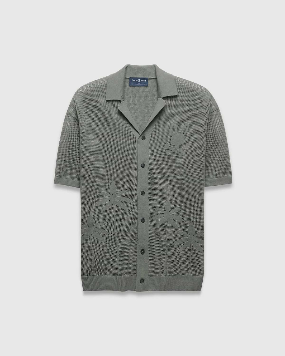 Mens Brad Oversized Knit Shirt in sage green, featuring an open knit texture, a large tonal Psycho Bunny skull logo on the left chest, and subtle palm tree patterns on the lower front.