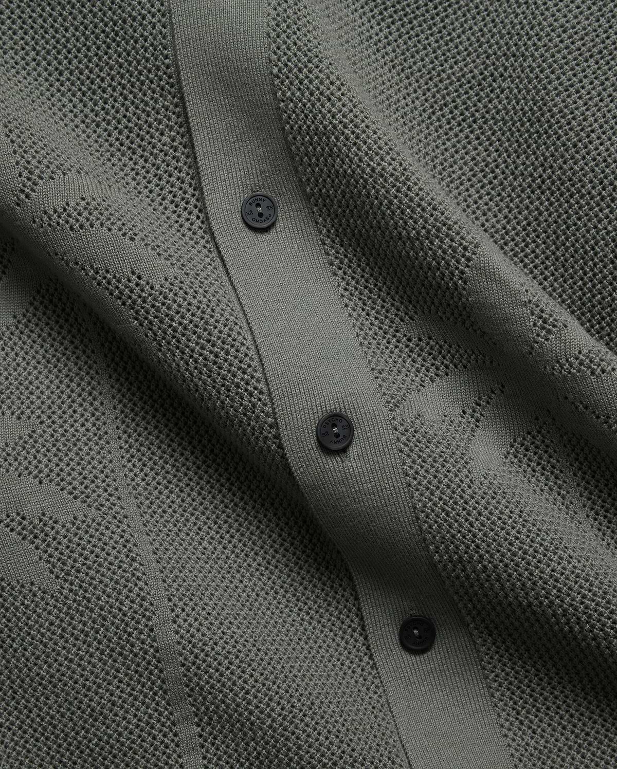 Mens Brad Oversized Knit Shirt in deep sage green, featuring a perforated openwork knit pattern, ribbed button placket, and dark branded Psycho Bunny buttons.