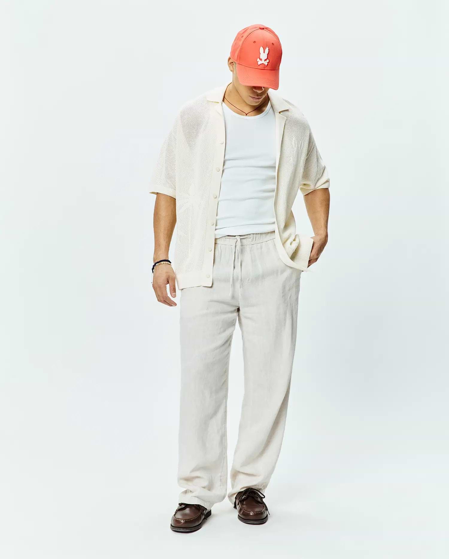 Mens Brad Oversized Knit Shirt in cream, a relaxed short-sleeve open-knit button-up, complemented by a coral Psycho Bunny skull logo baseball cap.