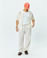 Mens Brad Oversized Knit Shirt in cream, a relaxed short-sleeve open-knit button-up, complemented by a coral Psycho Bunny skull logo baseball cap.