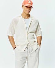 Mens Brad Oversized Knit Shirt in cream, featuring an open knit texture, relaxed fit, short sleeves, spread collar, and subtle woven palm tree pattern.