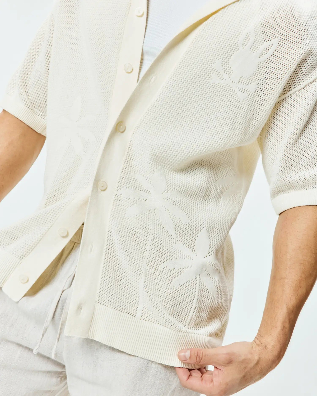 Mens Brad Oversized Knit Shirt in cream, featuring an open-knit texture with subtle palm leaf patterns and a large Psycho Bunny skull logo on the left sleeve.