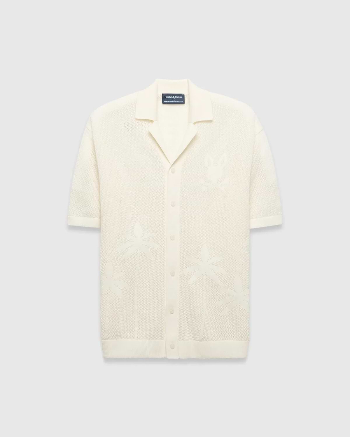 Mens Brad Oversized Knit Shirt in cream, with open-knit texture, subtle jacquard palm tree patterns, large jacquard Psycho Bunny skull logo on left chest, camp collar, and full button placket.