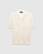 Mens Brad Oversized Knit Shirt in cream, with open-knit texture, subtle jacquard palm tree patterns, large jacquard Psycho Bunny skull logo on left chest, camp collar, and full button placket.