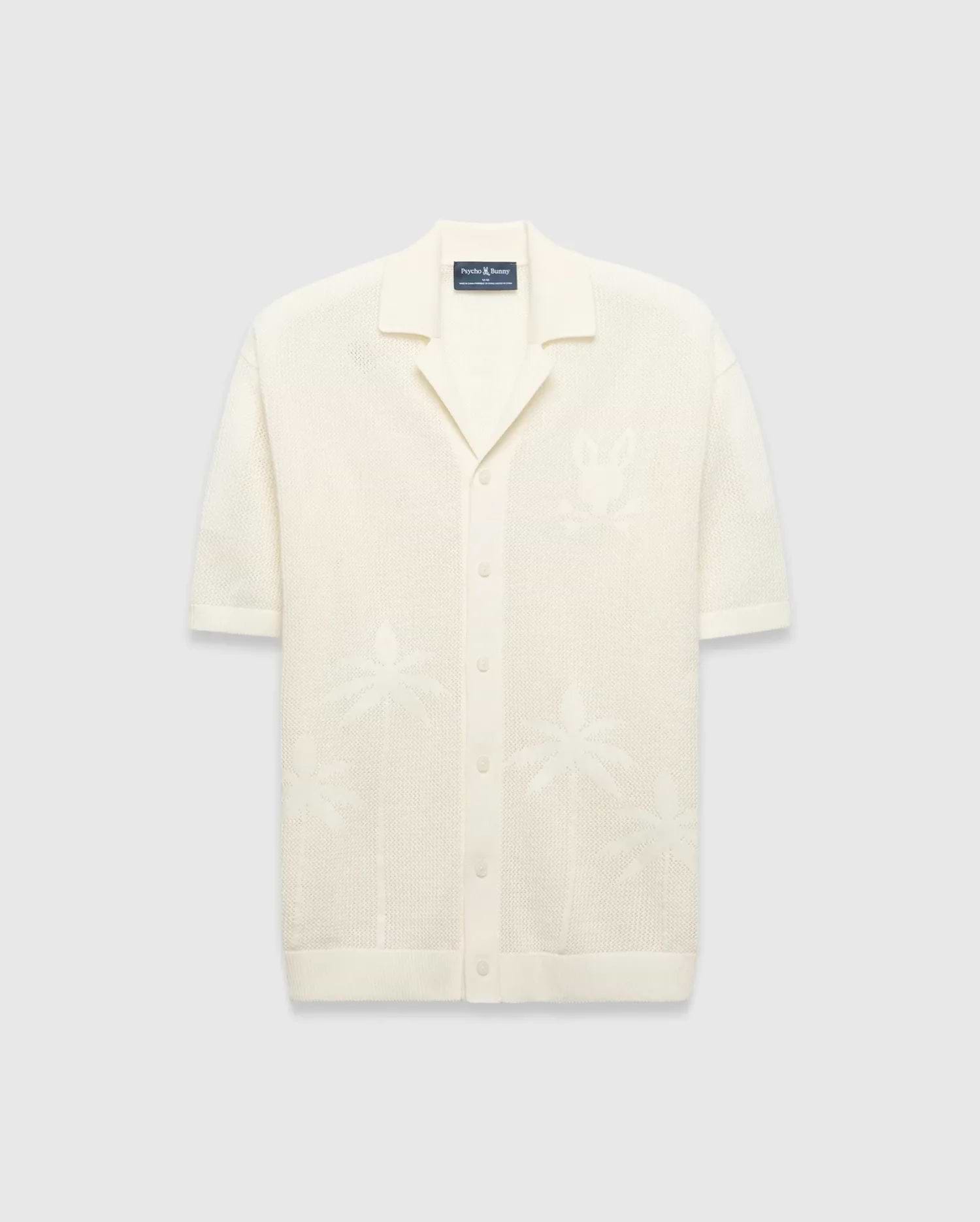 Mens Brad Oversized Knit Shirt in cream, with open-knit texture, subtle jacquard palm tree patterns, large jacquard Psycho Bunny skull logo on left chest, camp collar, and full button placket.