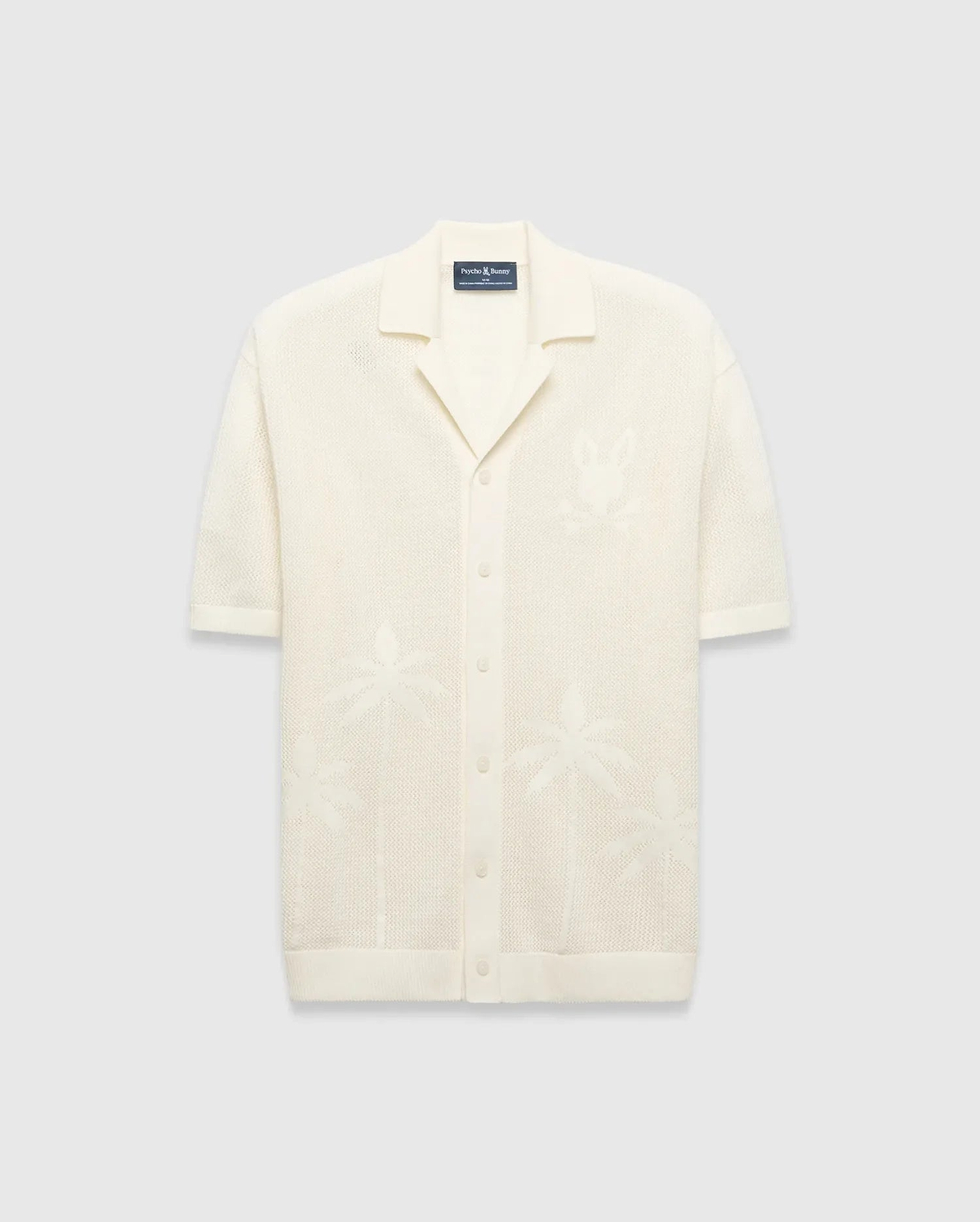 Mens Brad Oversized Knit Shirt in cream, with open-knit texture, subtle jacquard palm tree patterns, large jacquard Psycho Bunny skull logo on left chest, camp collar, and full button placket.