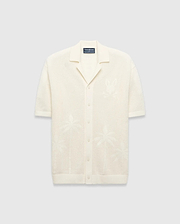 Mens Brad Oversized Knit Shirt in cream, with open-knit texture, subtle jacquard palm tree patterns, large jacquard Psycho Bunny skull logo on left chest, camp collar, and full button placket.