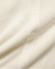 Cream Brad Oversized Knit Shirt with an open-knit texture, featuring a subtle, tone-on-tone Psycho Bunny skull pattern woven throughout and a button-front placket with cream buttons.