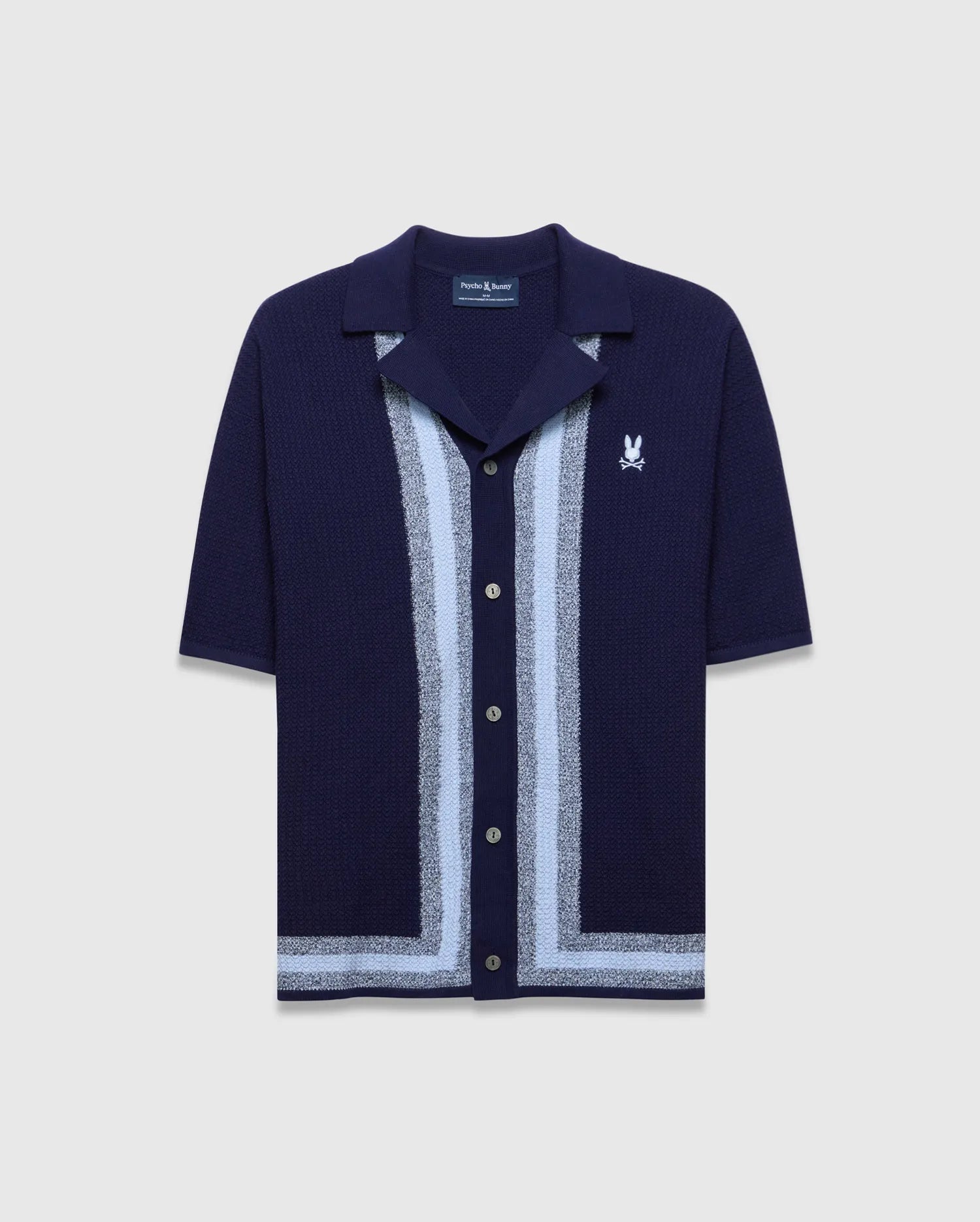 Mens Giles Relaxed Fit Border Knit Shirt in navy, featuring a textured knit, light blue and silver vertical stripes down the placket, a matching hem stripe, and a small white embroidered Psycho Bunny skull logo on the left chest.